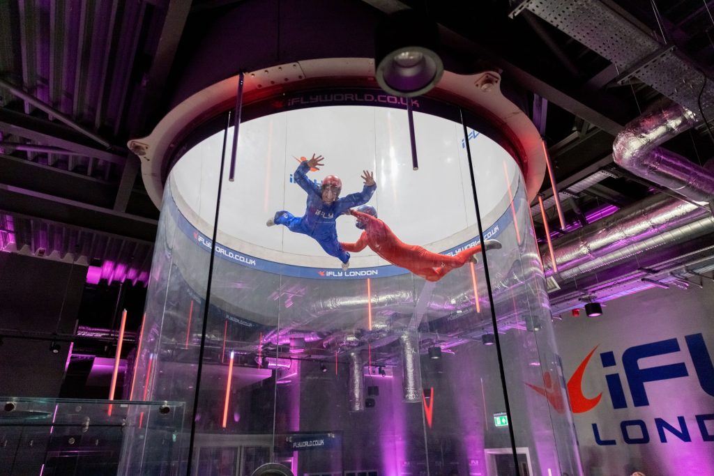 Indoor skydiving experience at iFLY London with two people in flight suits floating in air tunnel for a stag do event