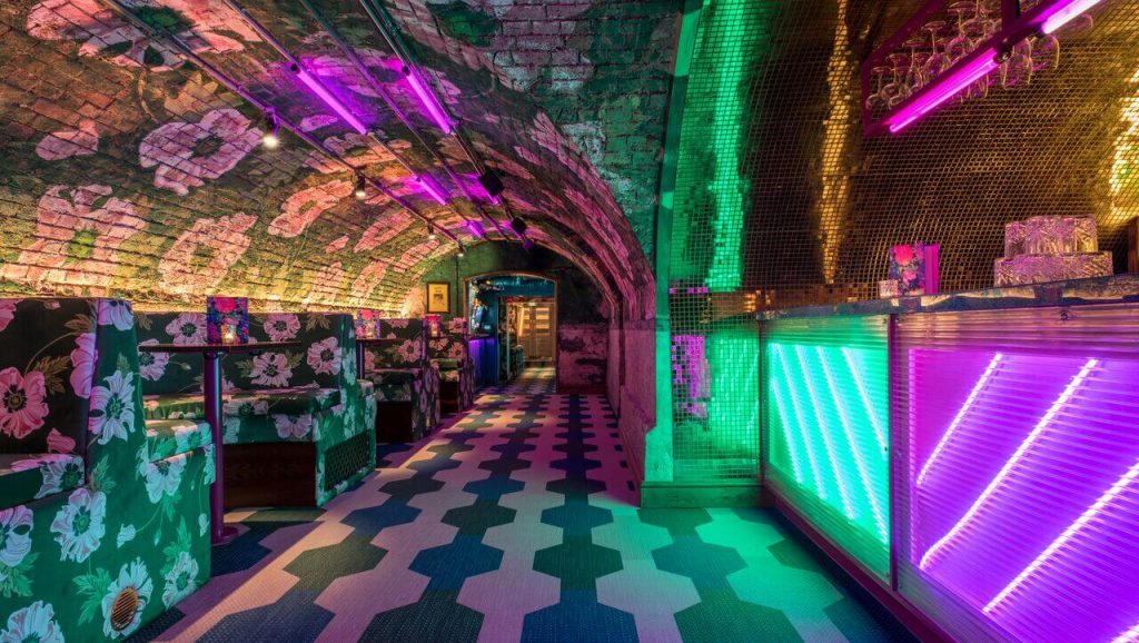 Vibrant and quirky interior of Blame Gloria bar in Covent Garden, London, with neon lights and patterned seats for a stag party