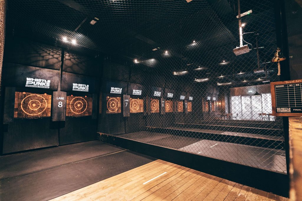Competitive axe-throwing lanes at Whistle Punks in London, with visible scoreboards and a safety net, set for an active stag do challenge