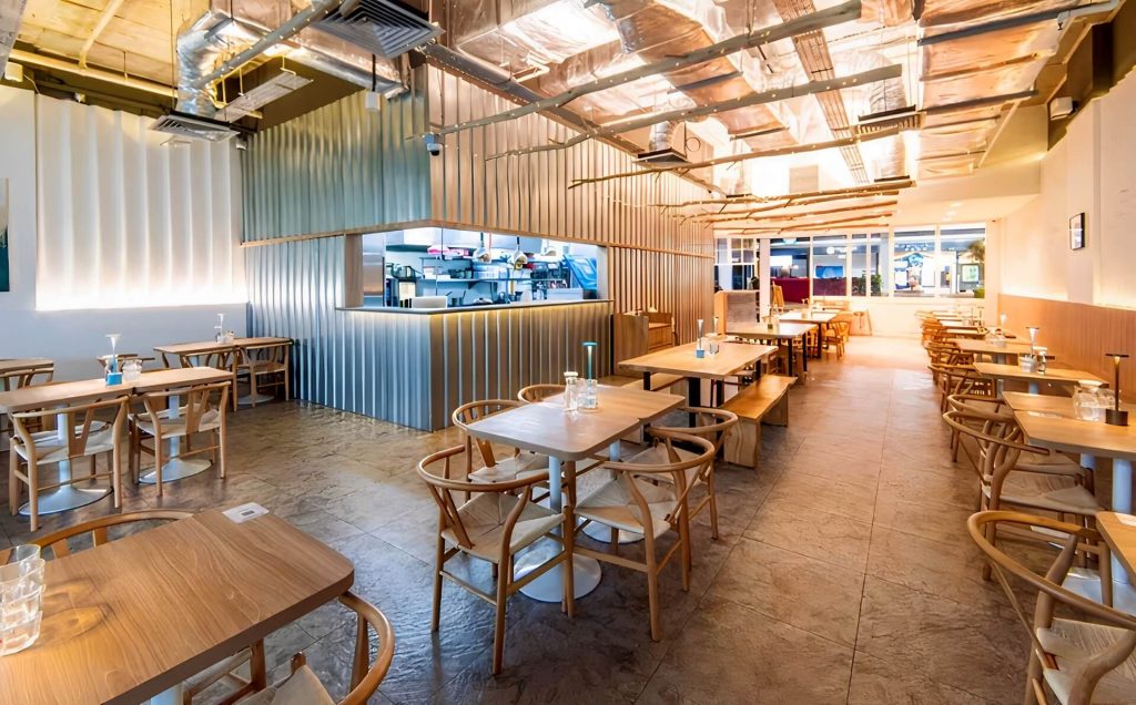 Interior of a café with wooden tables, chairs, and modern décor.