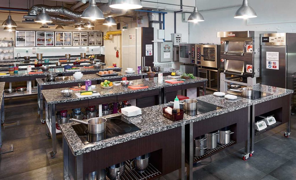 A professional kitchen setup with multiple cooking stations and stainless steel appliances.