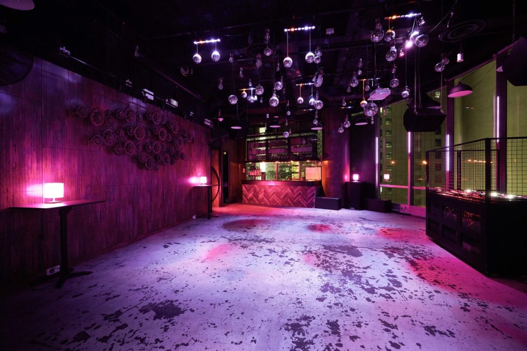 Interior of TUFF CLUB Singapore showing a dance floor with disco balls, pink lighting, and empty bar area awaiting a lively party.