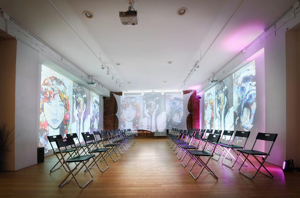 A spacious art gallery with projected images on the wall, set up for a unique group activity in NYC.