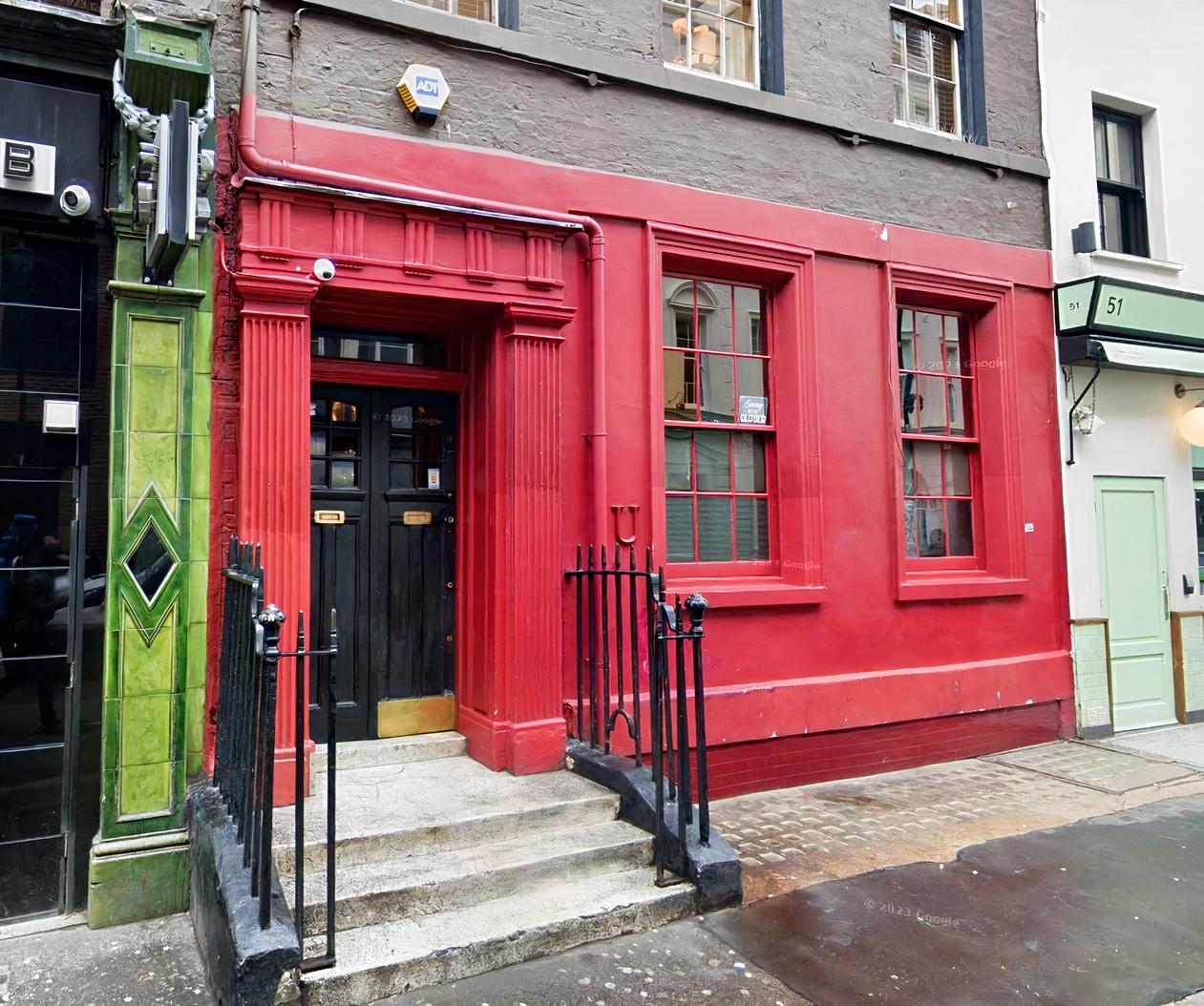 A red-painted building facade with tall windows and an ornate entryway at The Union Club