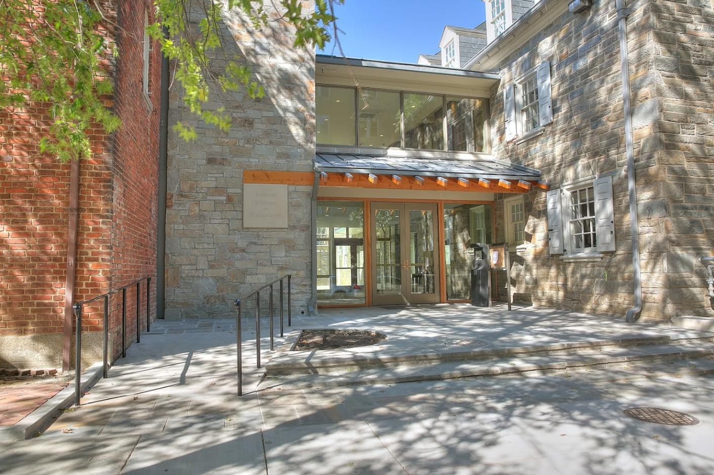 A historic building with stone exterior walls, large windows, and a glass entryway at Friends Meeting of Washington.