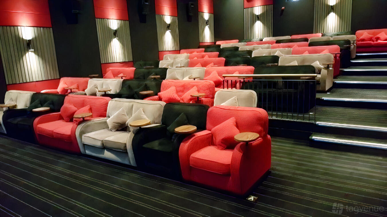 An auditorium with tiered plush seating, side tables, and wall sconces at Everyman Chelmsford