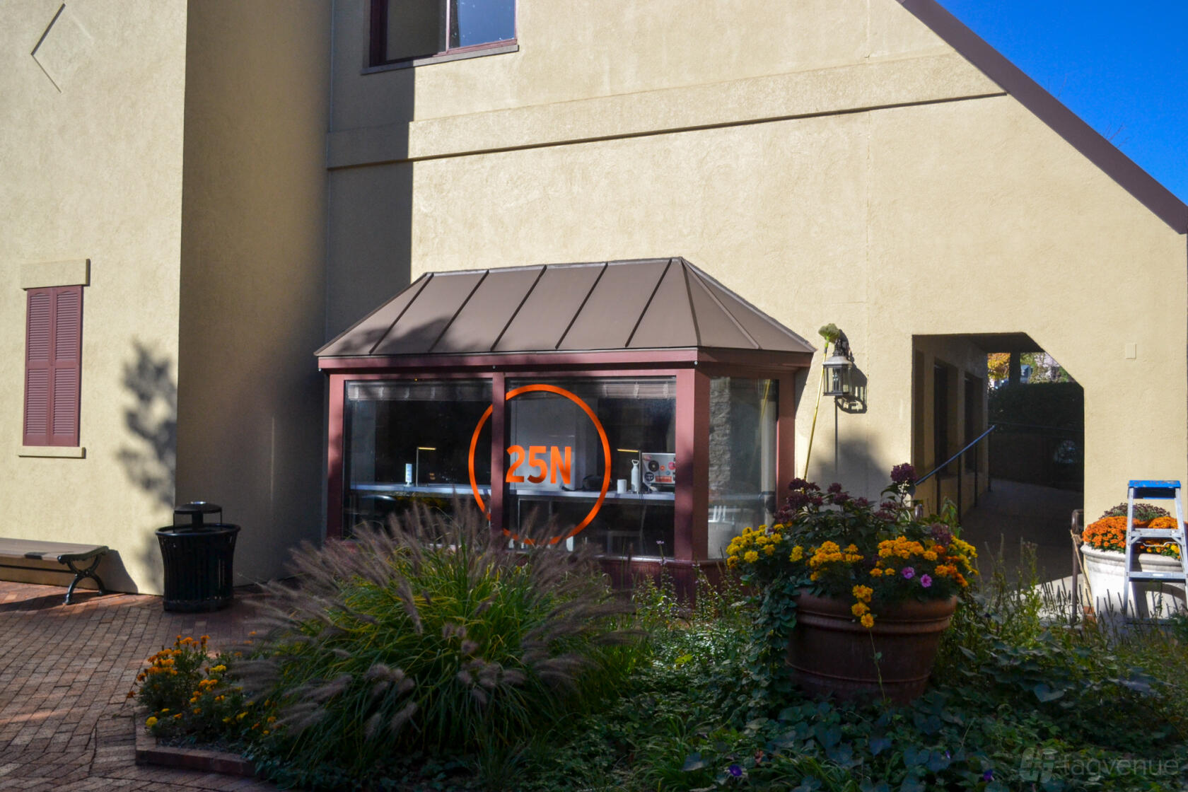 A coworking space with a glass entryway, potted flowers, and landscaped walkway at 25N Coworking Geneva.