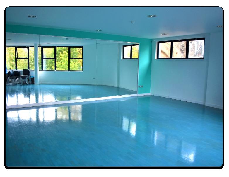A dance studio with mirrored walls, blue flooring, and large windows at Castlehaven Community Centre & Hub.