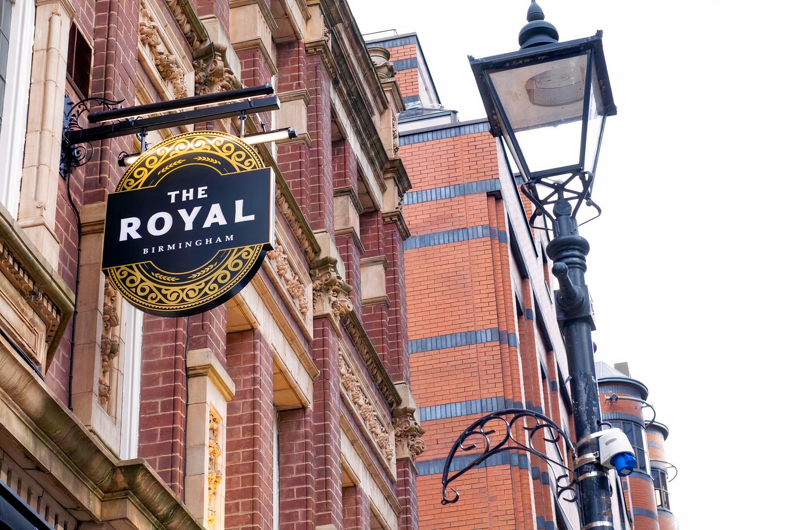A pub with a round hanging sign and ornate brick facade at The Royal.