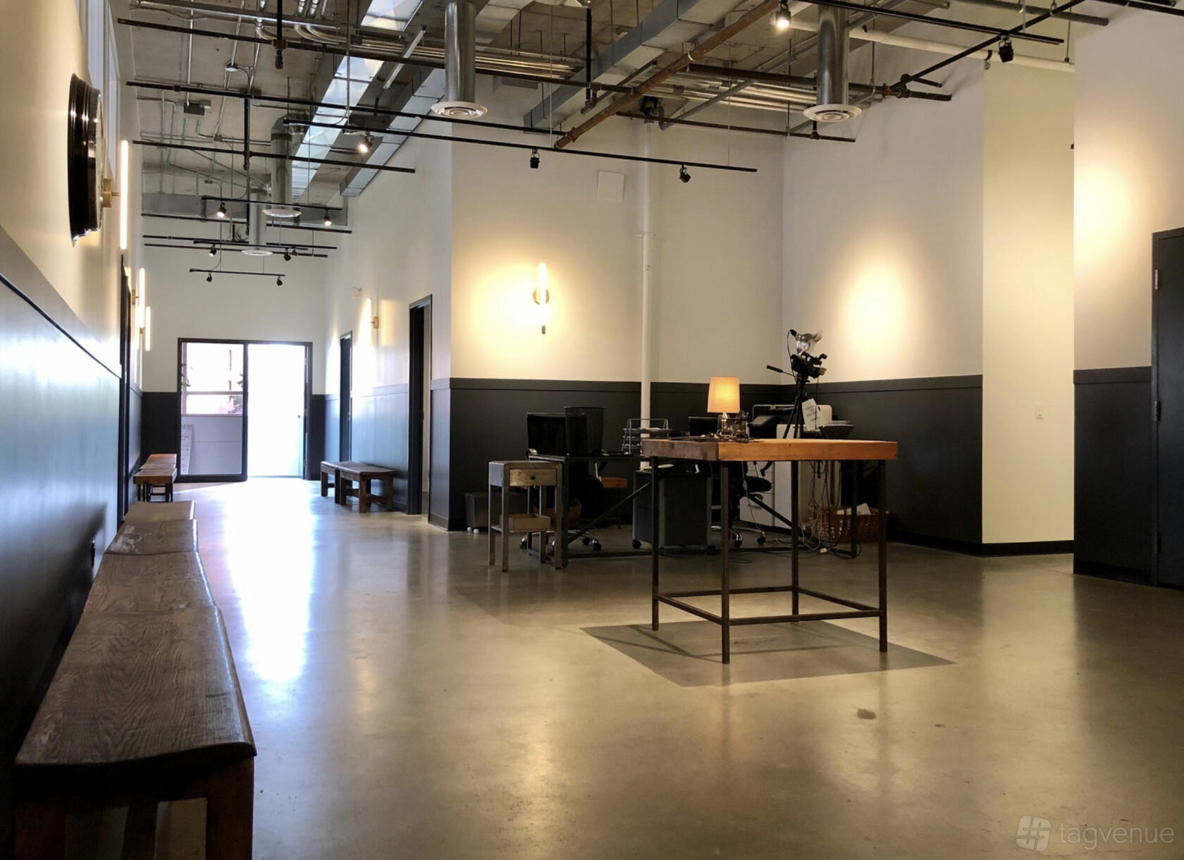 A photo studio with polished concrete floors, exposed ceilings, and a reception desk at Powerhouse Casting.