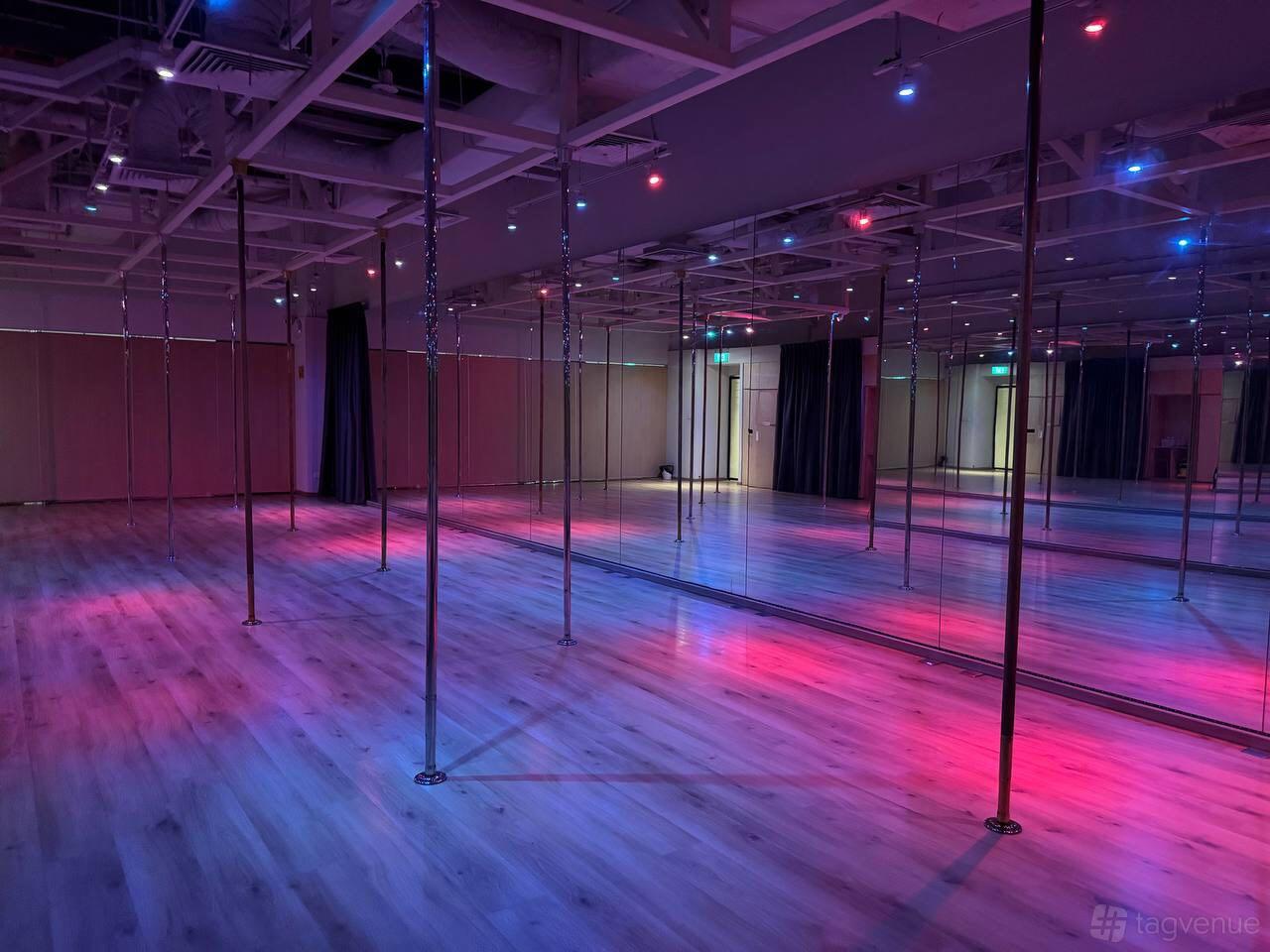 A dance studio with pole installations, mirrored walls, and colorful LED lighting at Diva Pole Academy.