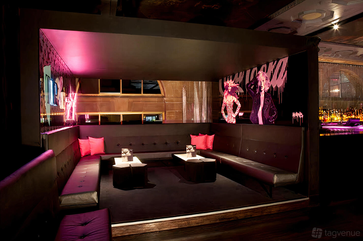 An event space in a nightclub with pink neon lighting, black tufted booth seating, and mural art at Ms Collins.
