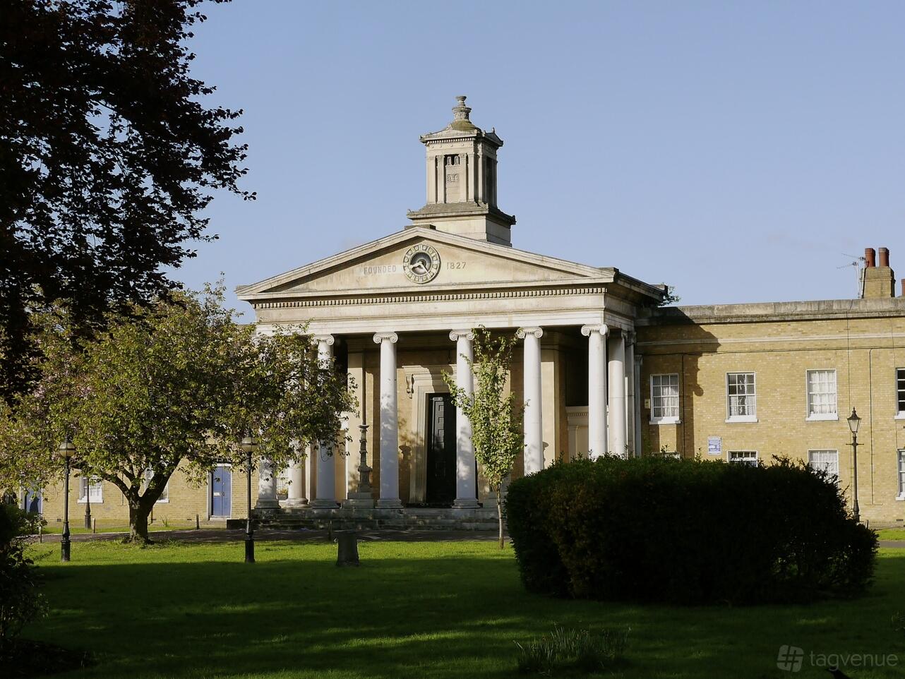 A historic building with tall white columns, large arched windows, and a grassy lawn at Asylum Chapel.