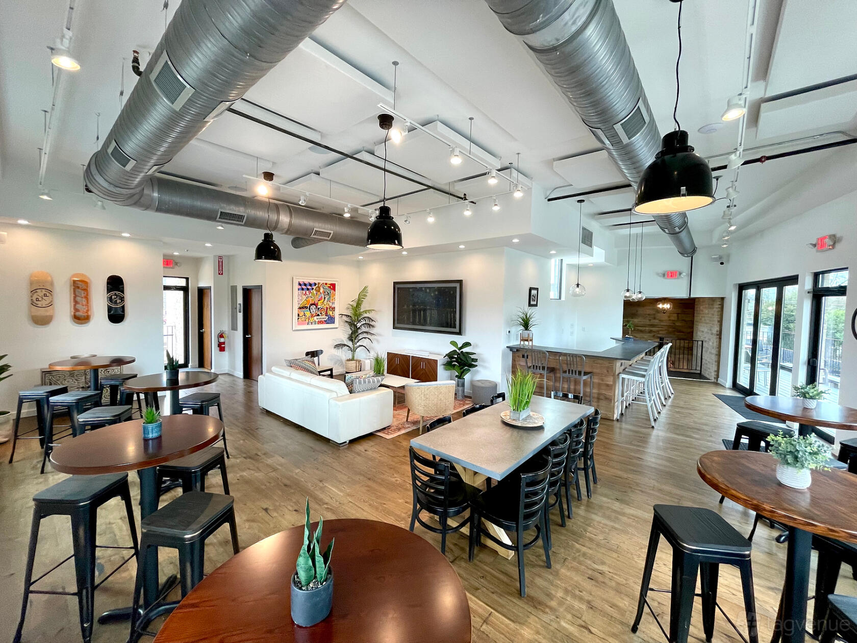 A restaurant with high ceilings, exposed ductwork, wooden floors, and a mix of lounge and dining seating at The Loft @ Paper Plane.