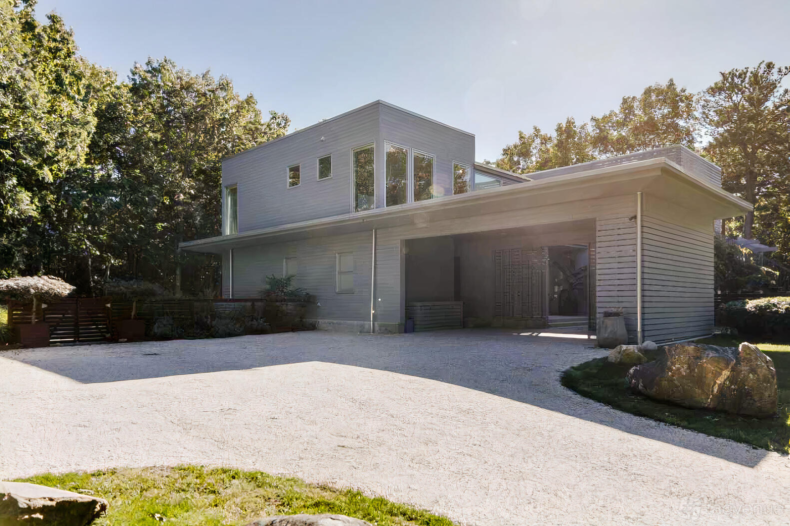 A country house with a modern wood exterior, large windows, and a gravel driveway at Casa Eximia.