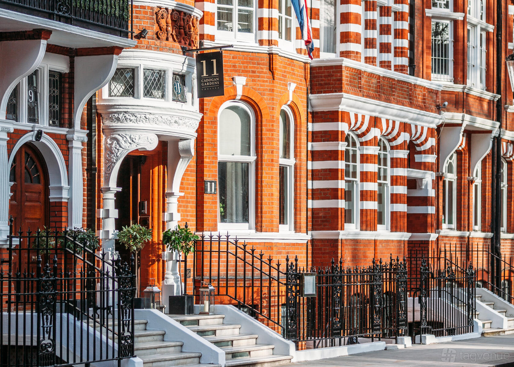 A hotel with red brick facade, white trim, ornate entry arch, and black wrought iron railings at 11 Cadogan Gardens.