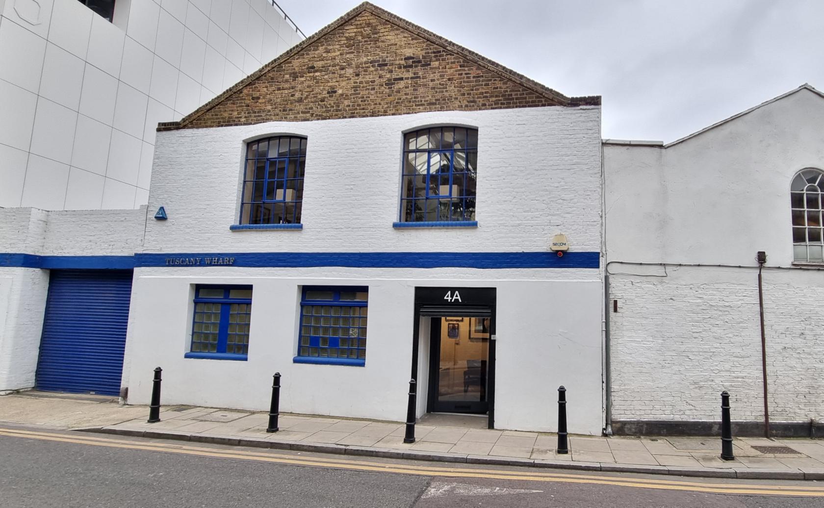 A versatile event space with a white painted brick exterior, blue trim, and arched windows at L'Atelier Hoxton.