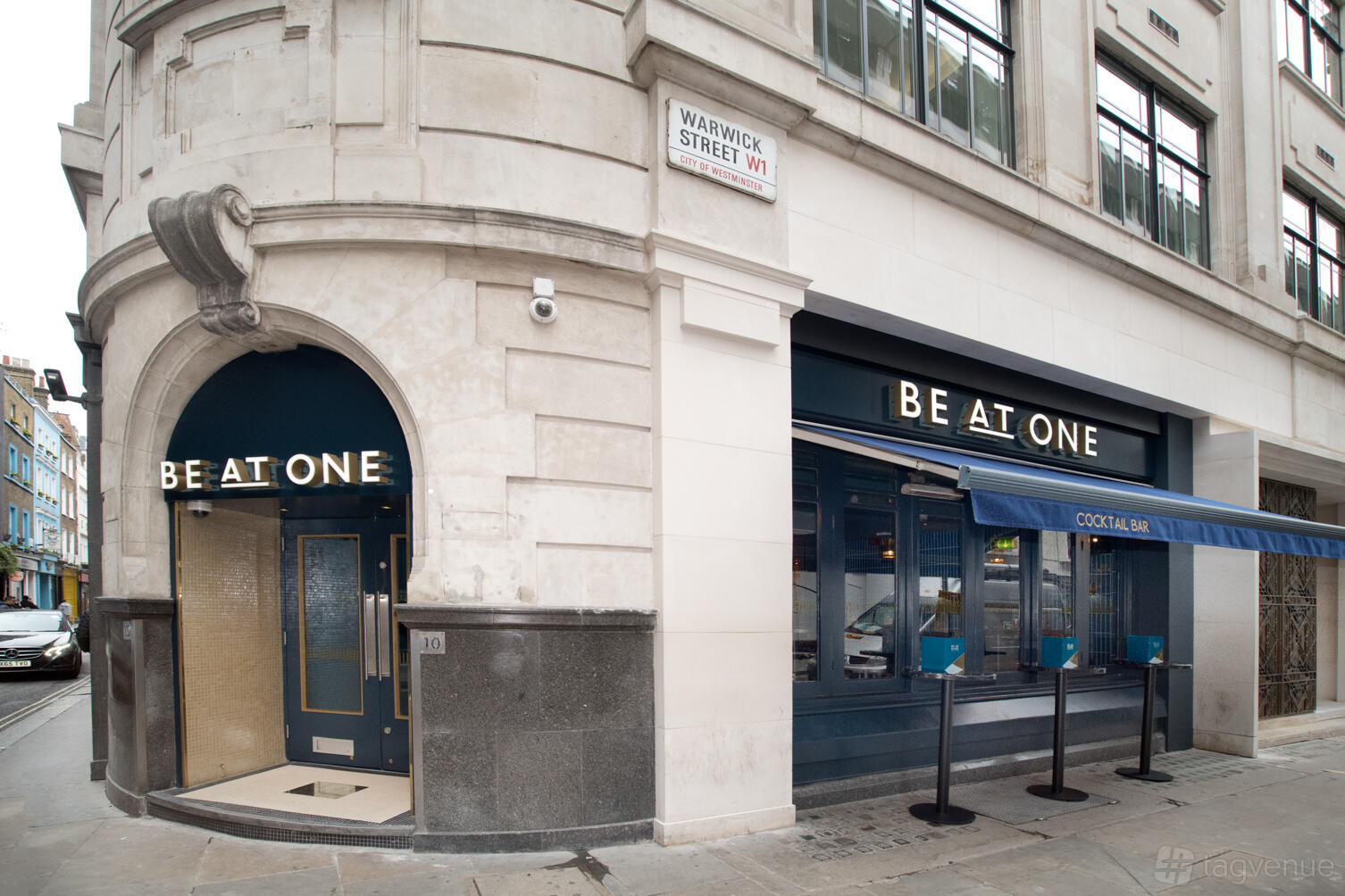 A corner pub with curved stone facade, navy blue entrances, and bold signage at Be at One Regent Street.