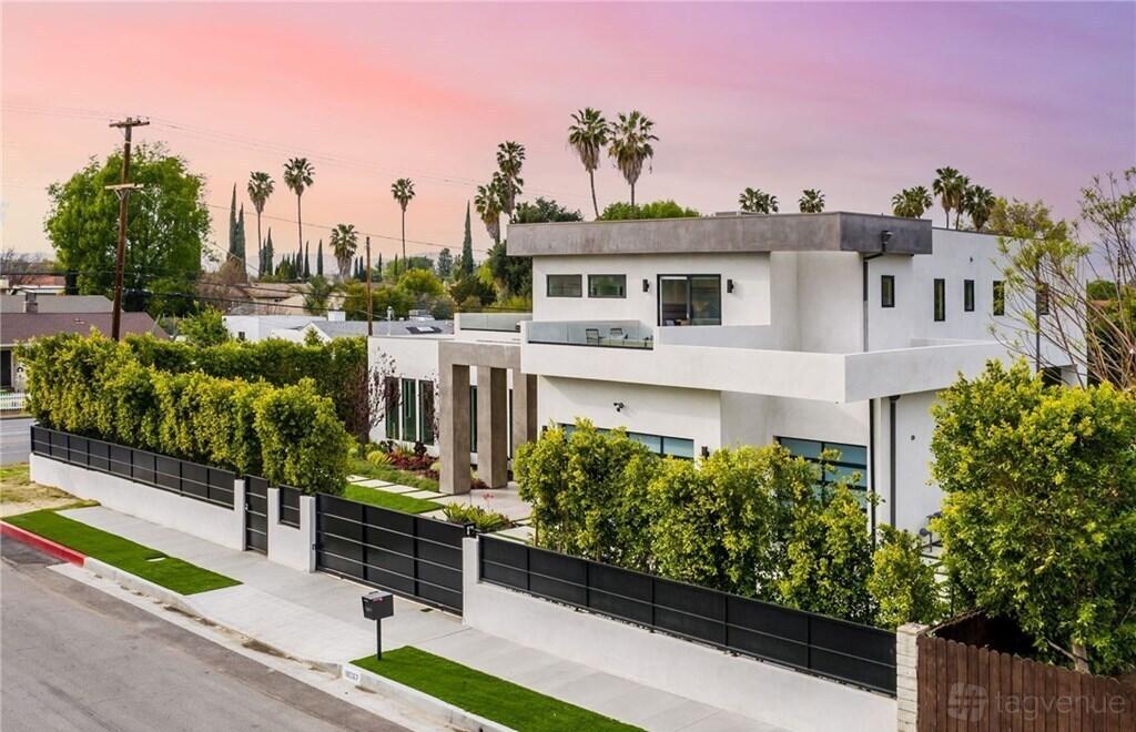A modern photo and film studio apartment with a white facade, large windows, and gated hedges at Mansion In LA.