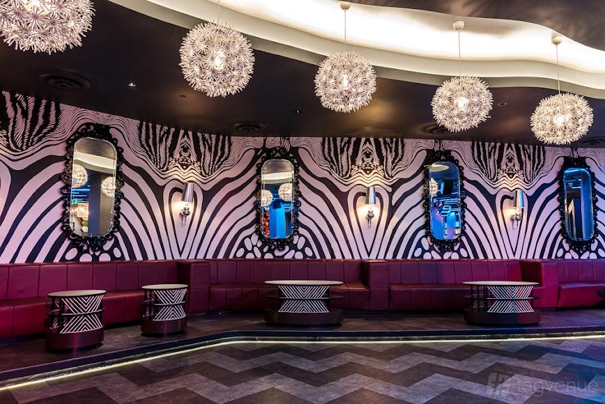 A nightclub lounge with red curved couches, zebra print walls, and ornate mirrors at Time Nightclub.
