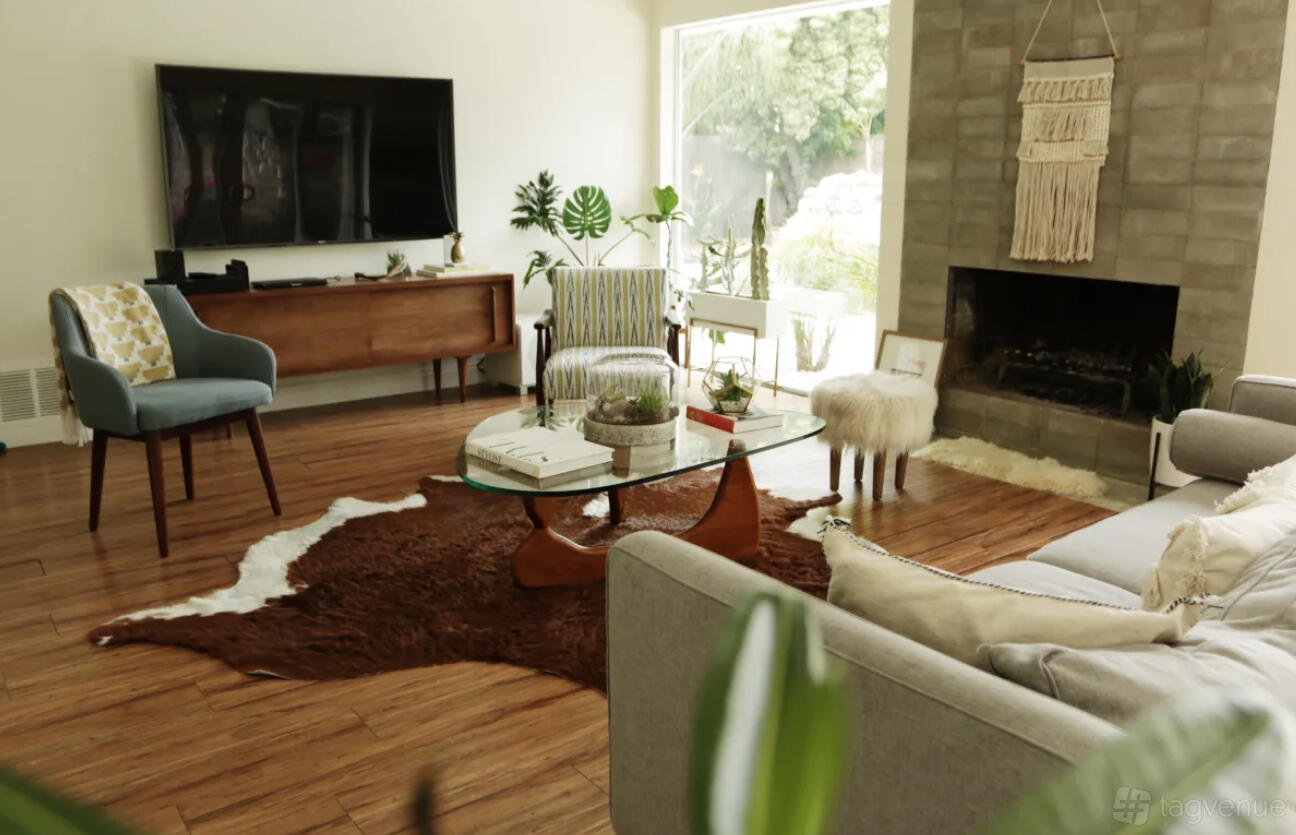 An event venue with hardwood floors, mid-century furniture, a stone fireplace, and large window at Beautiful Mid century house.