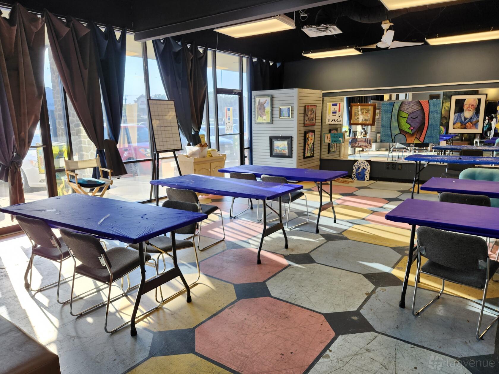 A community centre with large windows, patterned flooring, purple tables, and art displays at Central Arts of Bedford.