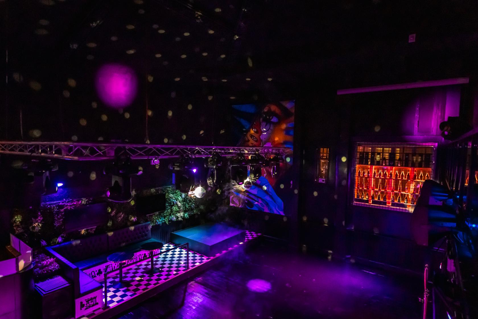 An event venue in a nightclub with purple lighting, a checkered dance floor, and wall art at Ghost Nottingham.