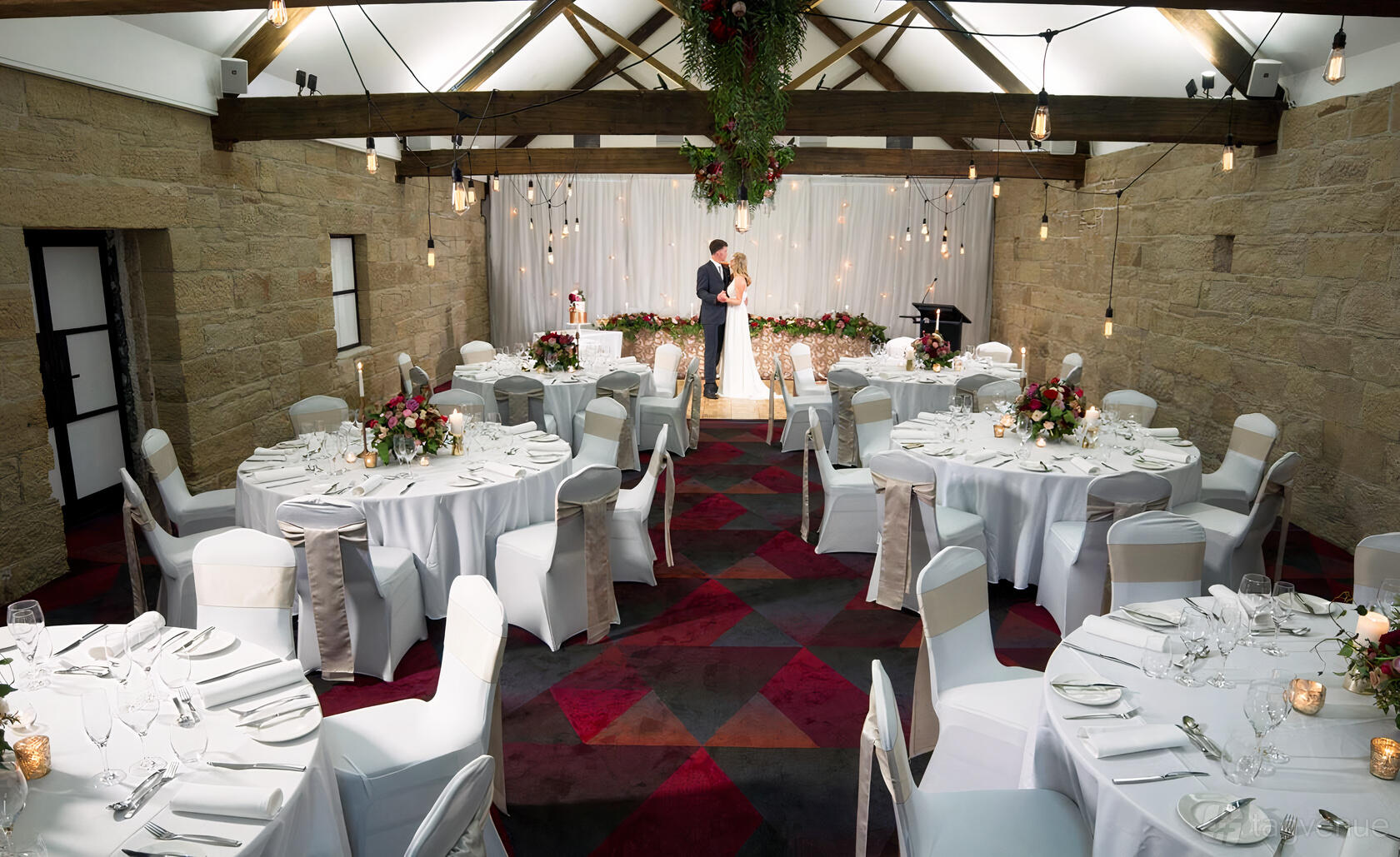 An event space with exposed stone walls, vaulted ceilings, and round tables with white linens at RACV Hobart Hotel.