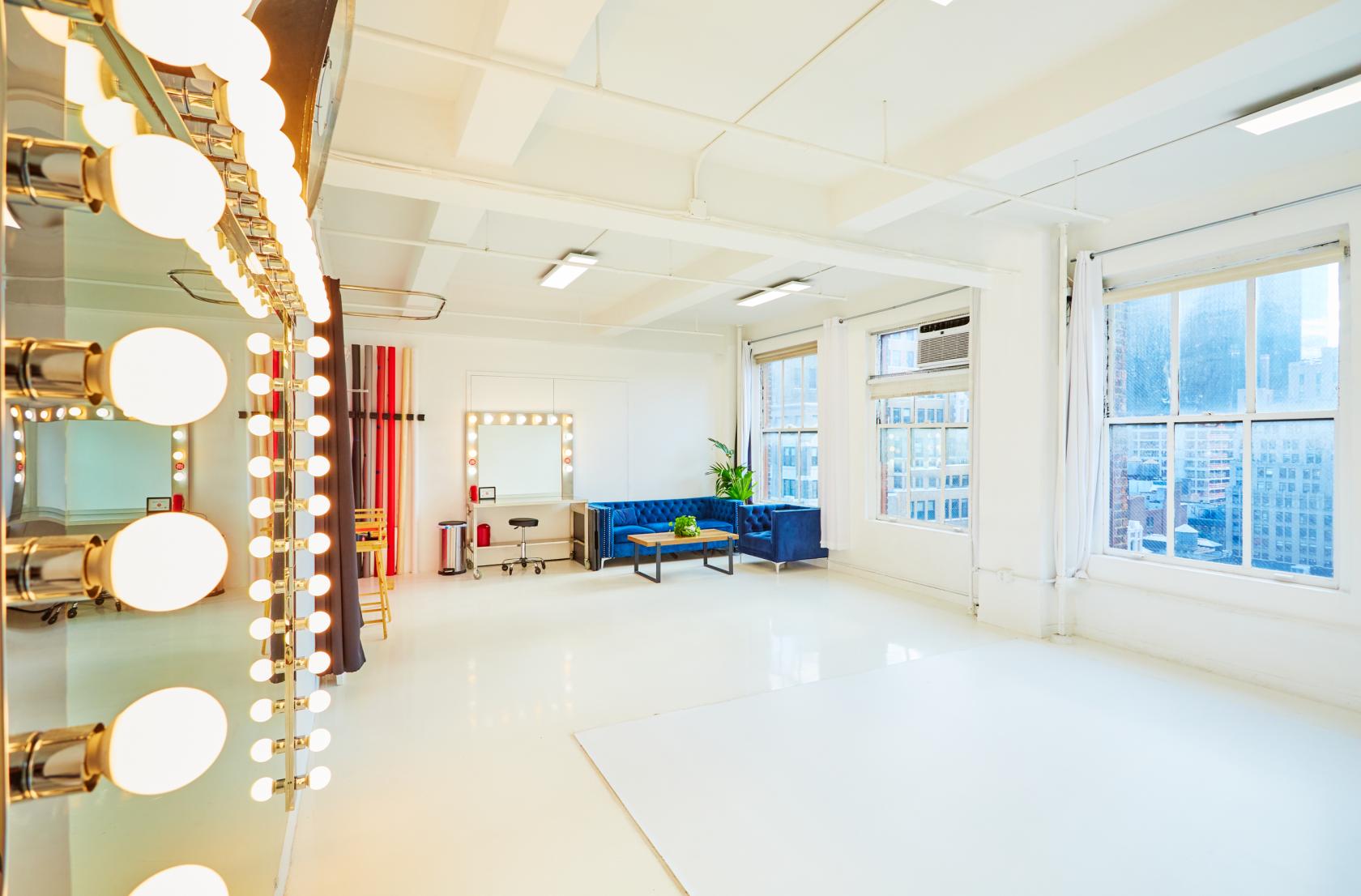 An event venue with large windows, white floors, and a wall of dressing room lights at Event Venue NYC Manhattan 22nd Floor.