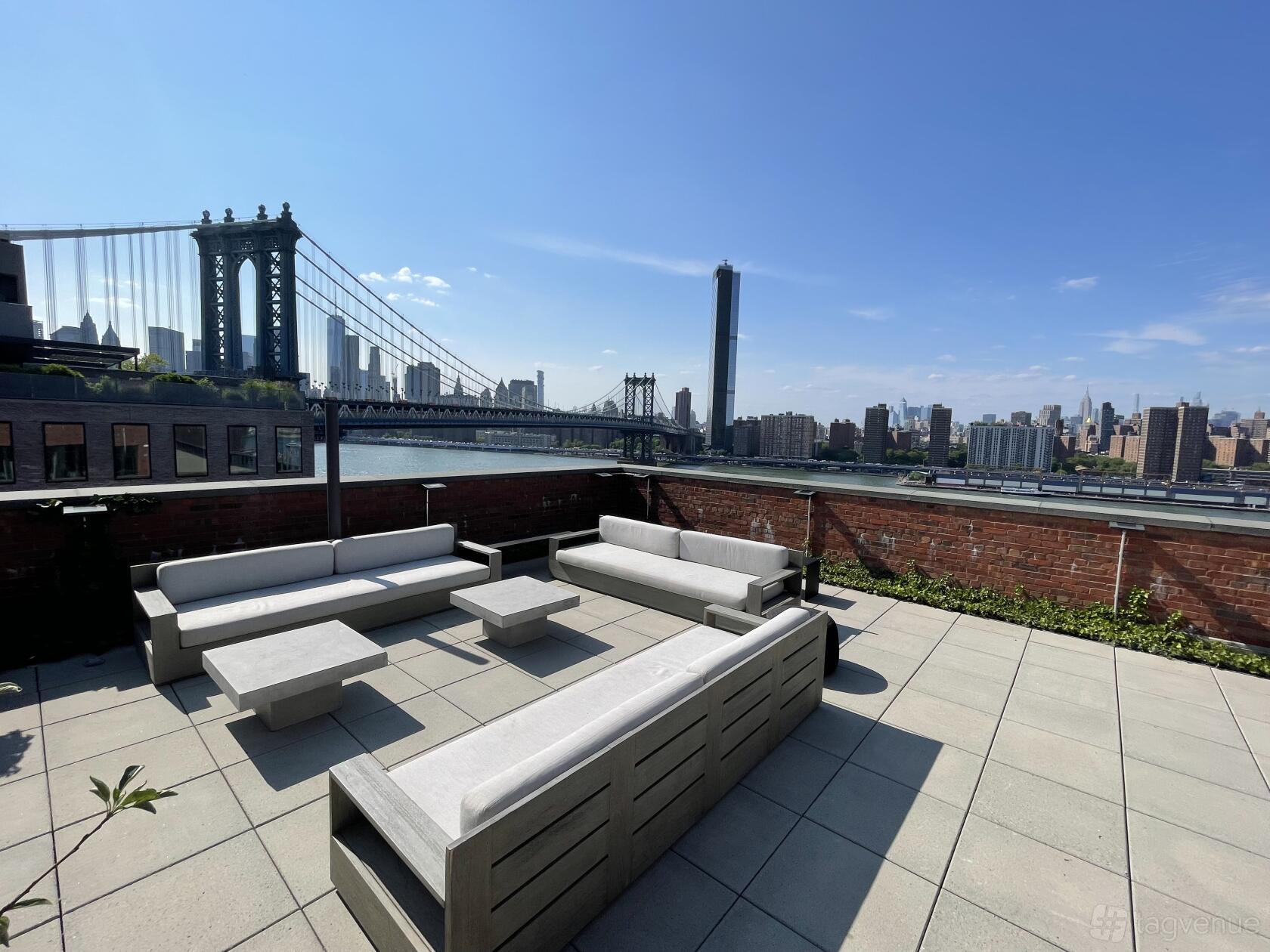 A rooftop space with outdoor lounge seating, potted plants, and city skyline views at Waterfront Rooftop at Dumbo 10 Jay Street.