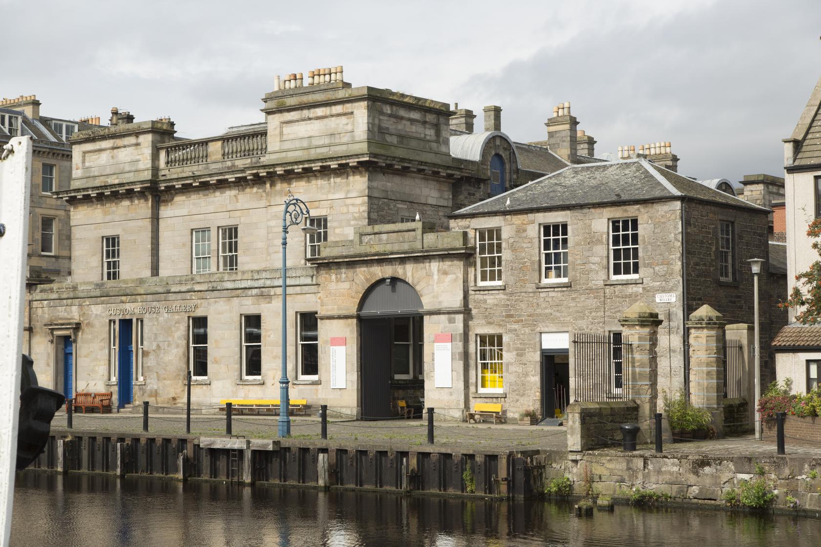 A versatile event space with stone facade, large arched windows, and canal-side location at Custom Lane.