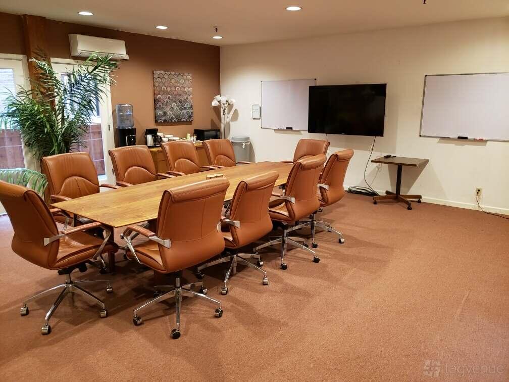 A meeting room with a long wooden conference table, brown leather chairs, and whiteboards at 350 Townsend.