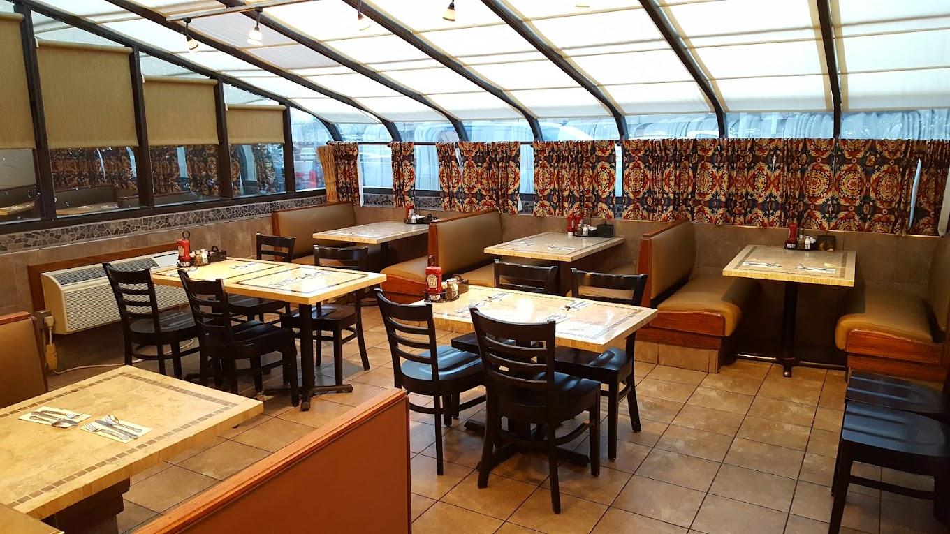 A restaurant with tiled floors, wooden tables, black chairs, and a glass ceiling at Crossroads Restaurant.