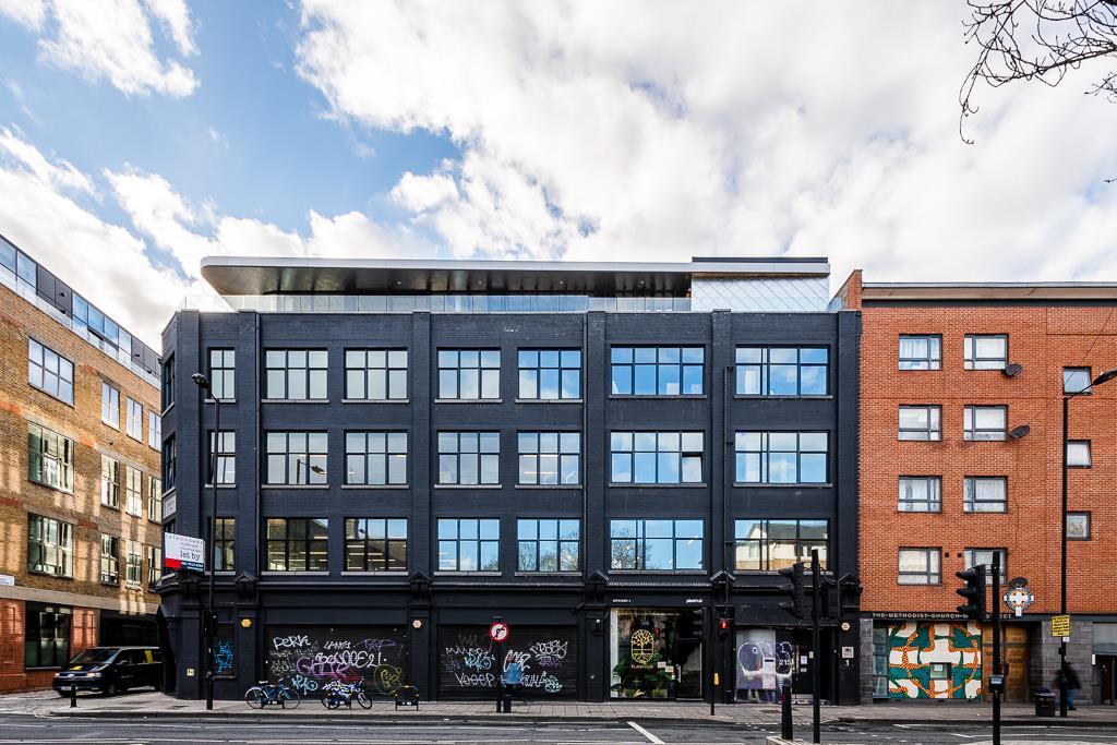 A film and photo studio with a black facade, tall windows, and street art on the ground level at Soif Studios.