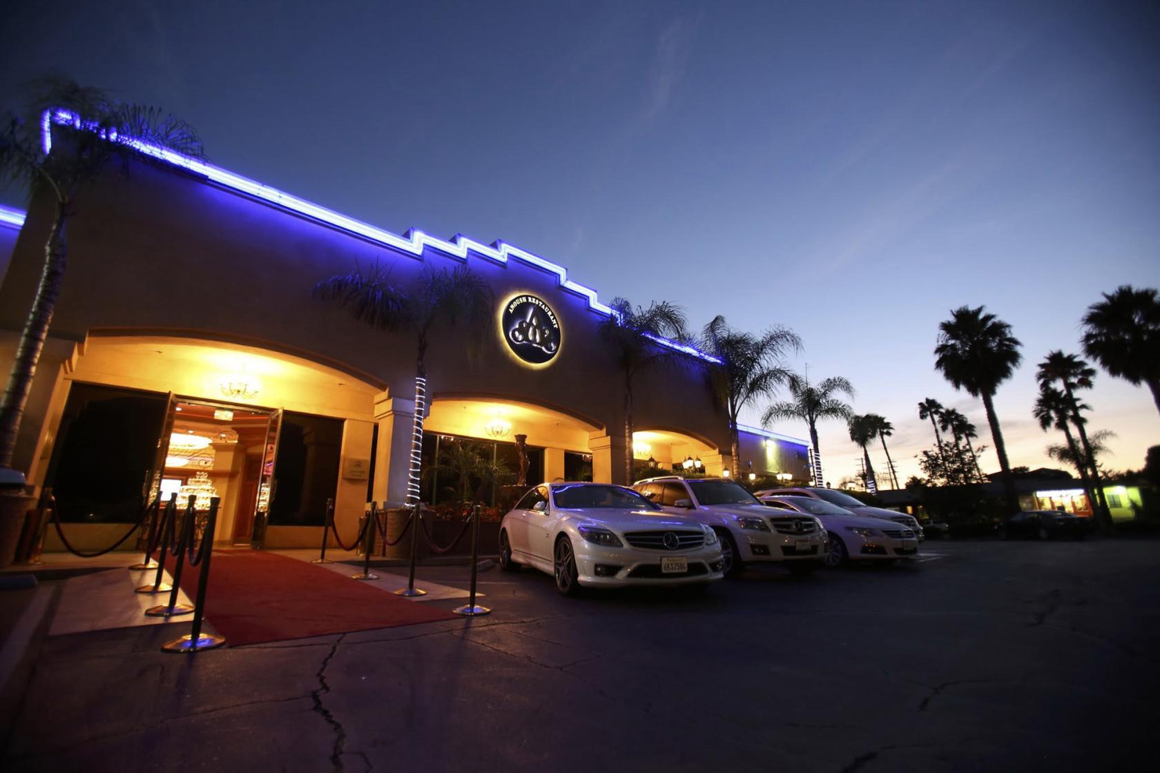 A hall with a grand entrance, blue accent lighting, palm trees, and a red carpet at Glenoaks Ballroom.