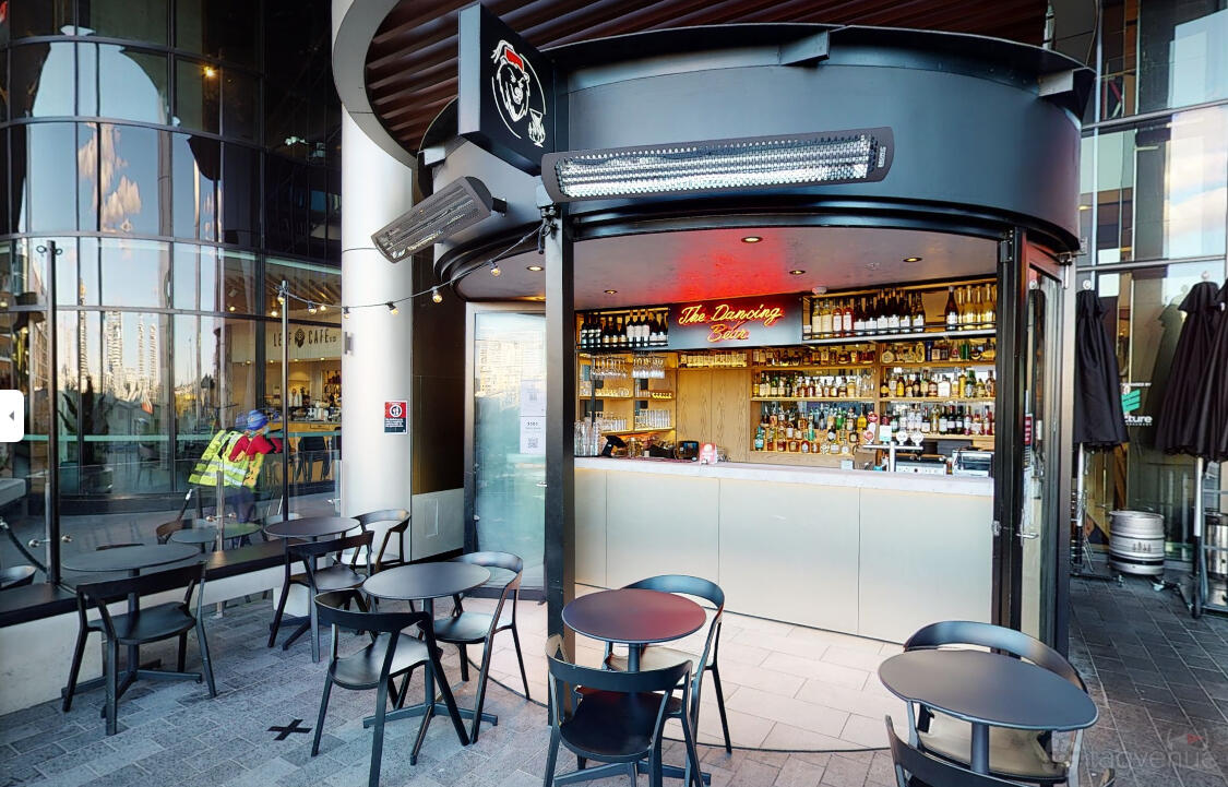 A bar with outdoor seating, round black tables, and a well-stocked counter at The Dancing Bear.