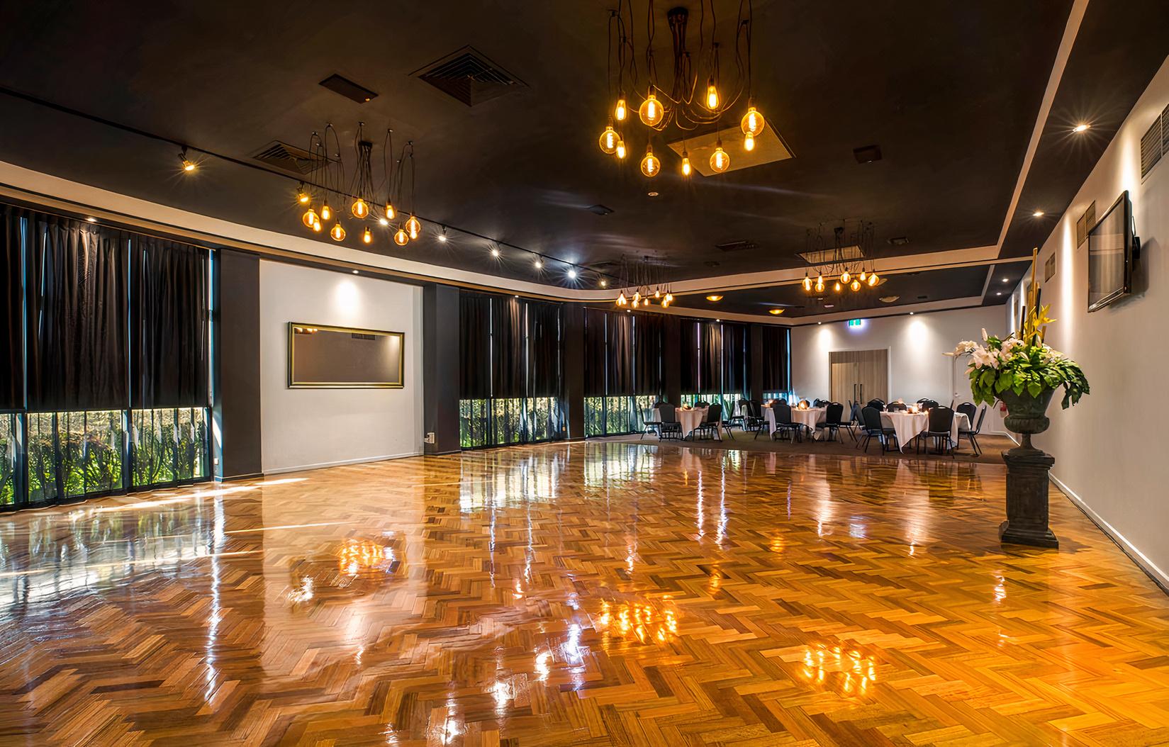 A banqueting hall with polished parquet flooring, pendant lighting, and floor-to-ceiling windows at The Seaford Hotel.