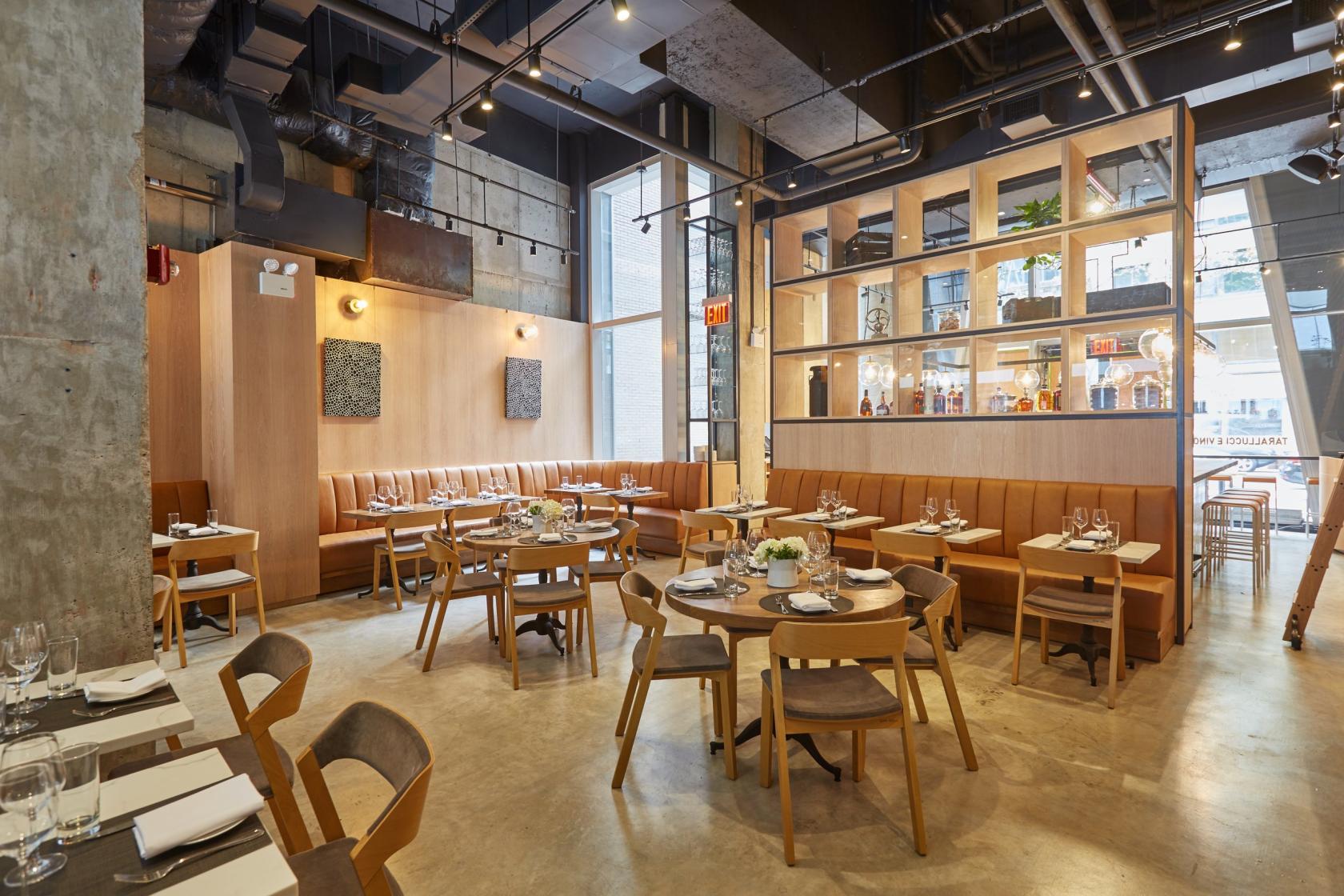 An event space in a restaurant with floor-to-ceiling windows, wood paneling, and tan banquette seating at Tarallucci e Vino NoMad.