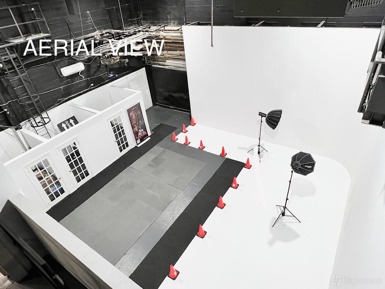 A photo studio with a white cyclorama wall, studio lighting, and black flooring at The Arena Studios.