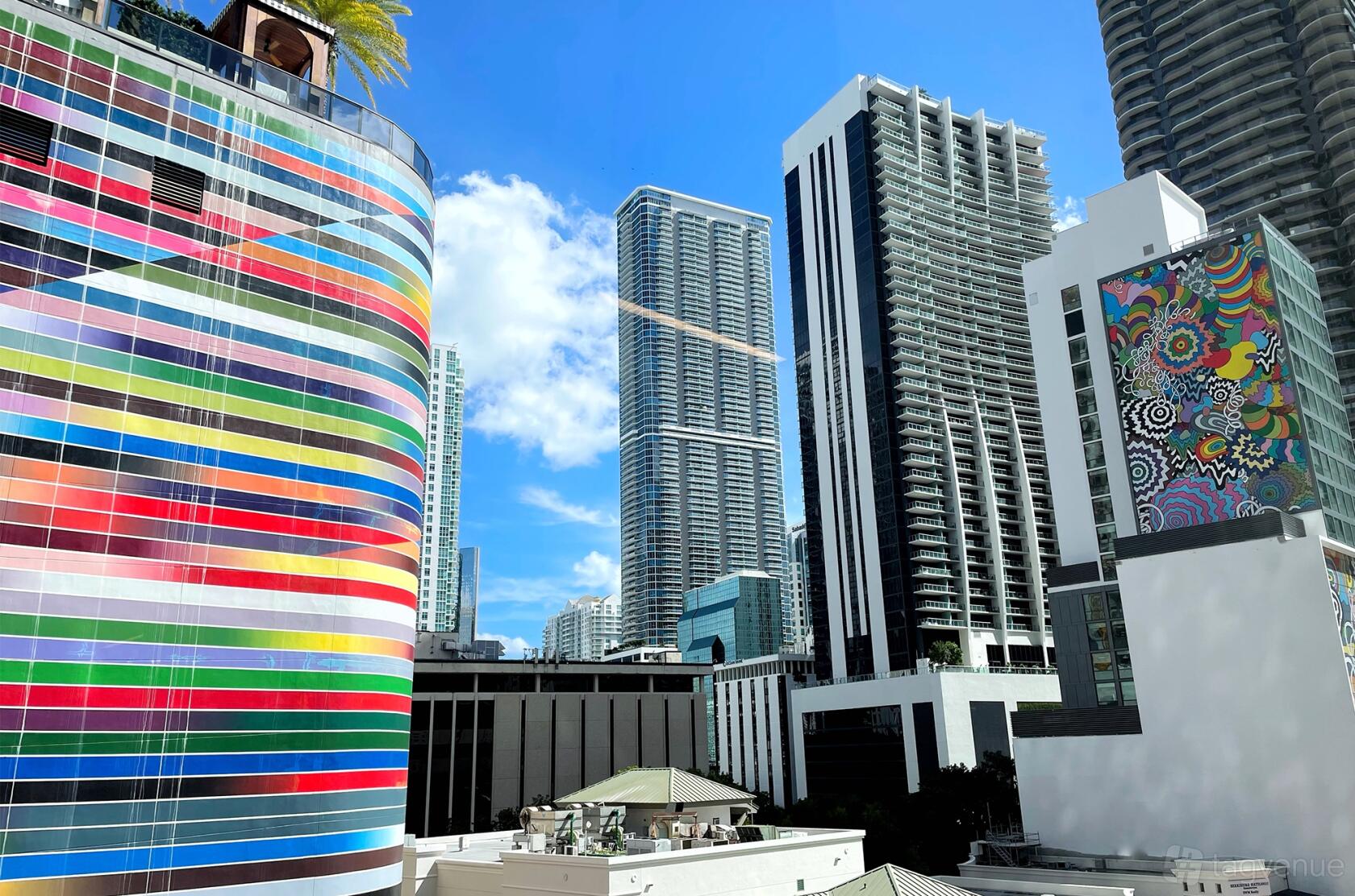A coworking space with views of colorful murals and tall buildings through large windows at Co-Work LatAm Brickell.