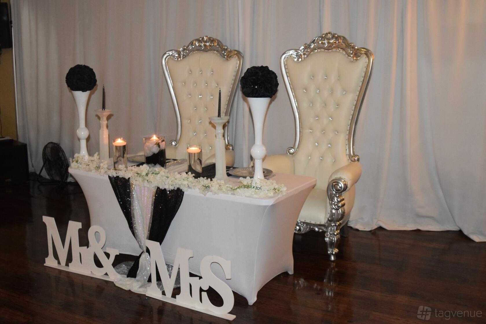 A hall with ornate high-back chairs, a draped backdrop, and a decorated sweetheart table at Forever Swing Dallas Event Center.
