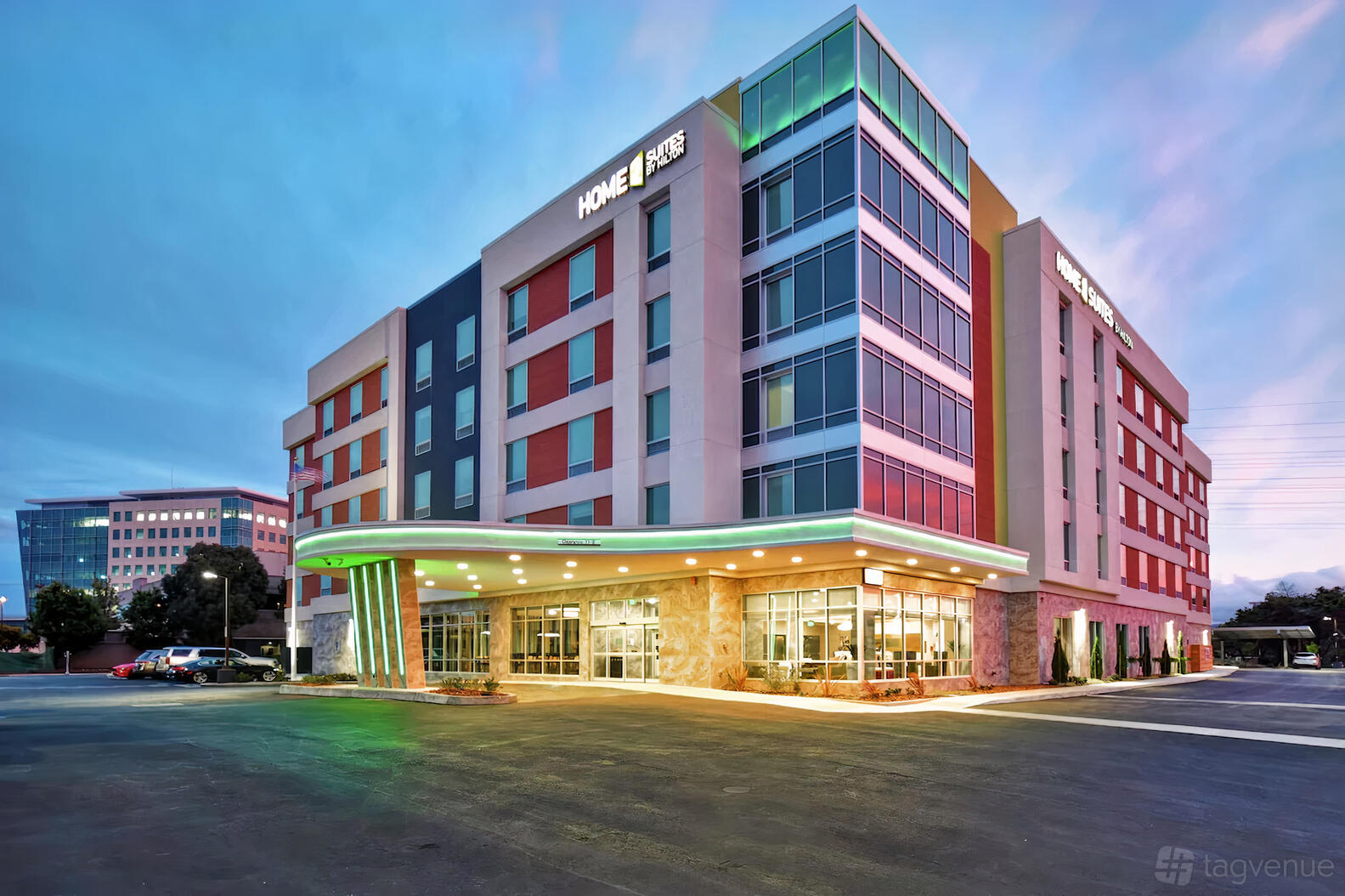 A modern hotel with a multicolored exterior facade, large front windows, and a covered entrance at Home2 Suites.