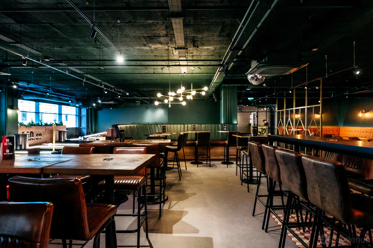 A bar with high tables, leather barstools, exposed ceiling and a modern chandelier at Par 59.