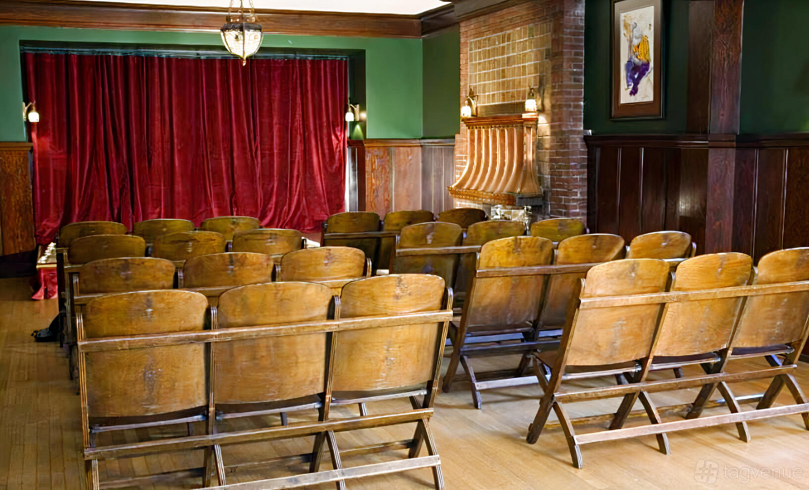 A screening room with wooden theater seats, red velvet curtains, and a brick fireplace at Shafer Baillie Mansion Bed & Breakfast.