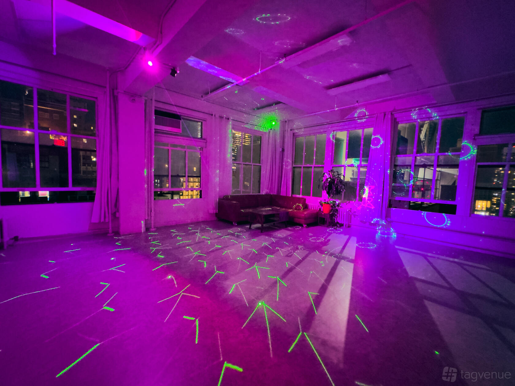 An event space in a loft with floor-to-ceiling windows, city night views, laser lighting, and lounge seating at Event Rental Space Manhattan 23rd Floor.