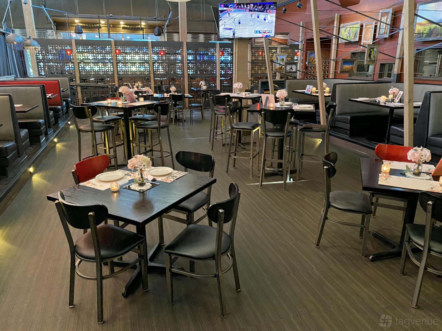 A dining room with dark wooden tables, black chairs, booth seating, and small floral centerpieces at Half Day Brewing.