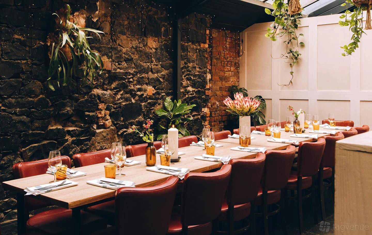 An event space in a pub with exposed stone walls, skylight ceiling, and long wooden table at The Grace Darling Hotel.