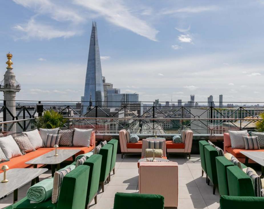 A rooftop lounge with cushioned seating, marble tables, and city skyline views at Wagtail.
