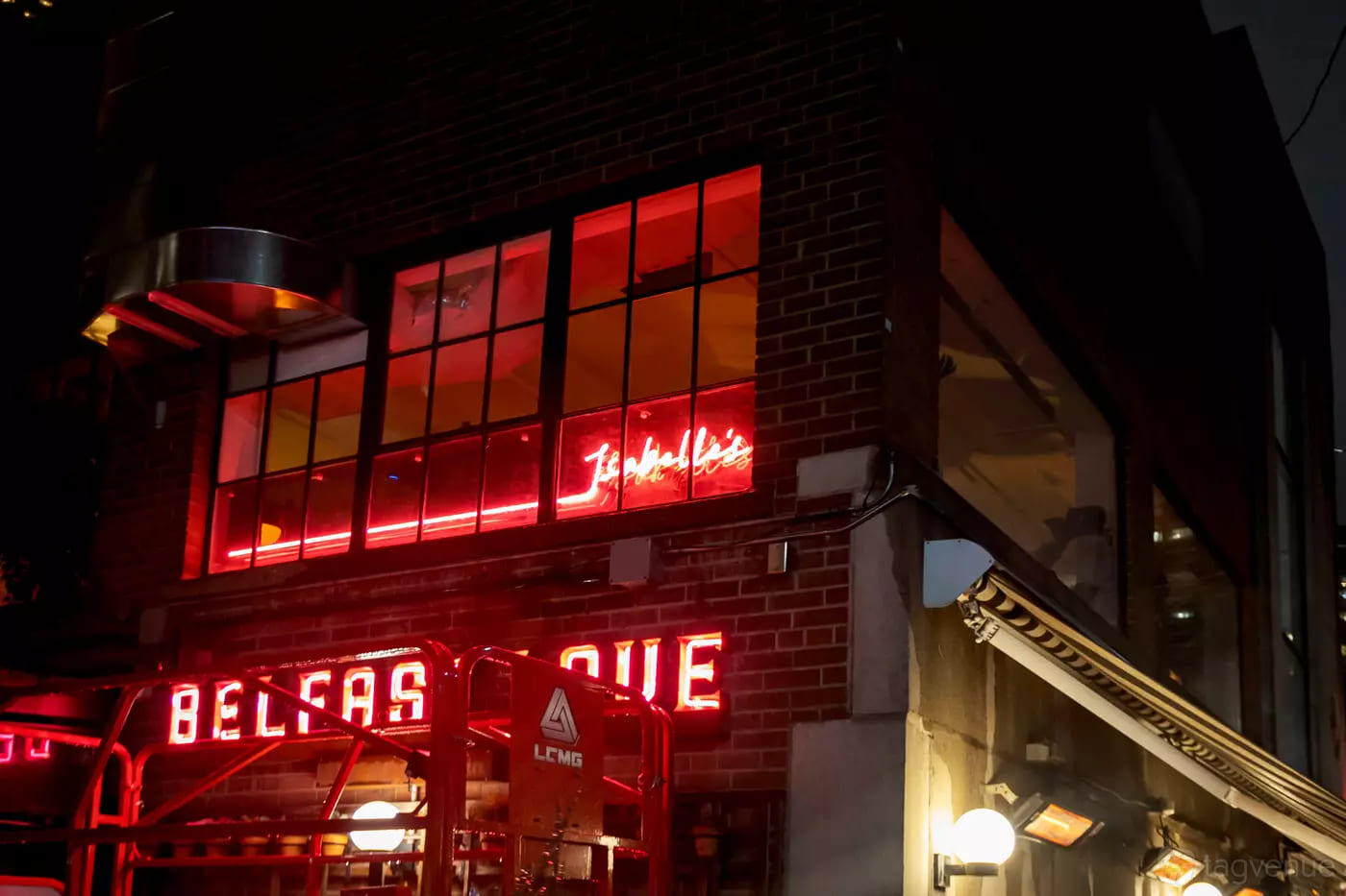 A nightclub exterior with brick walls, large windows, and bright red neon signage at Isabelle's Toronto.