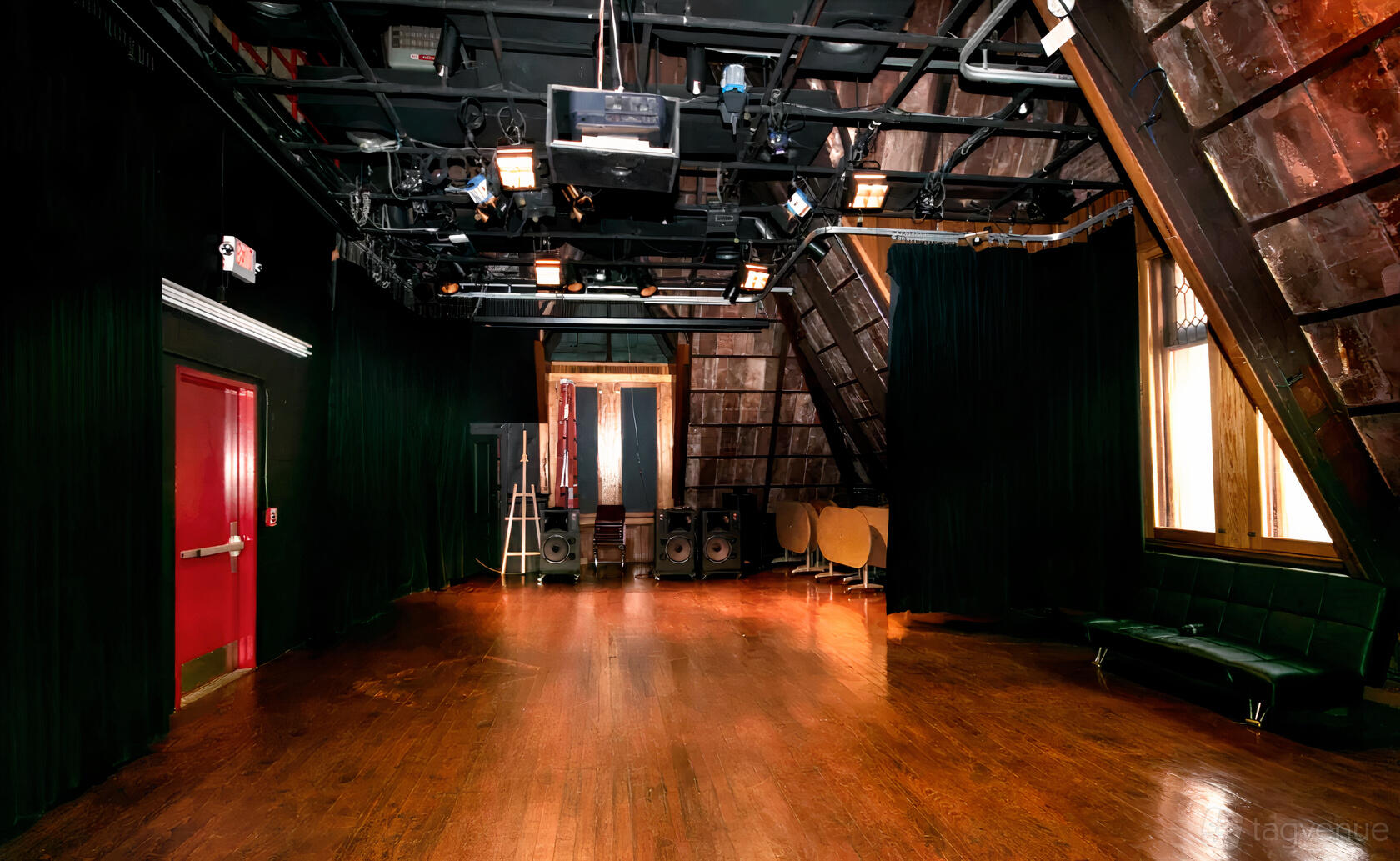 An event space with hardwood floors, theatrical lighting, and dark curtains at Downtown Community Television Center.